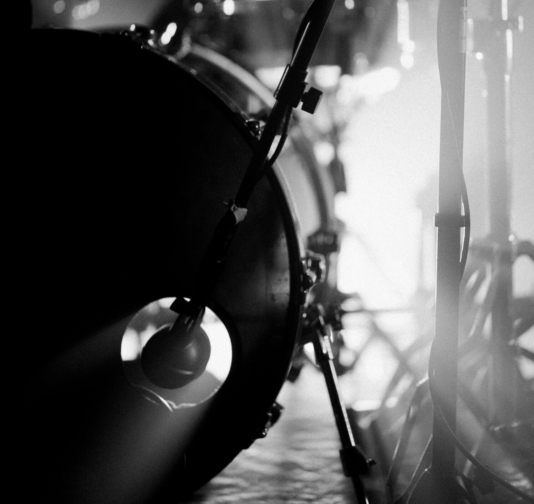 Artistic black and white close-up of a drum set on stage with dramatic lighting effects.